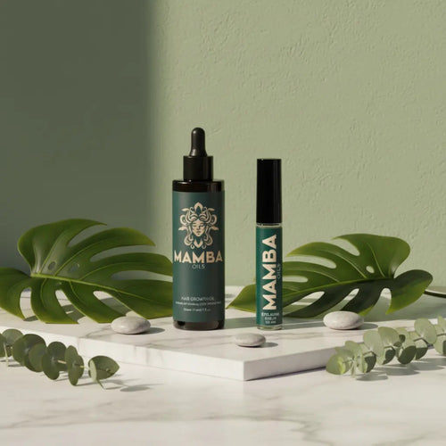 Two Mamba oil bottles on a white surface with green leaves and stones.