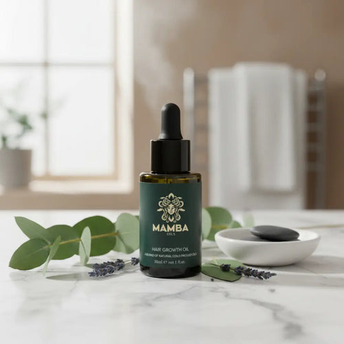 Mamba hair growth oil bottle on a marble surface with green leaves and a bowl in the background