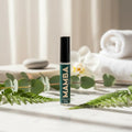 Mamba skincare serum bottle on a white surface with greenery and towels in the background