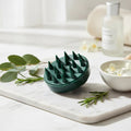 Green textured bowl on a marble surface with greenery and a bottle in the background