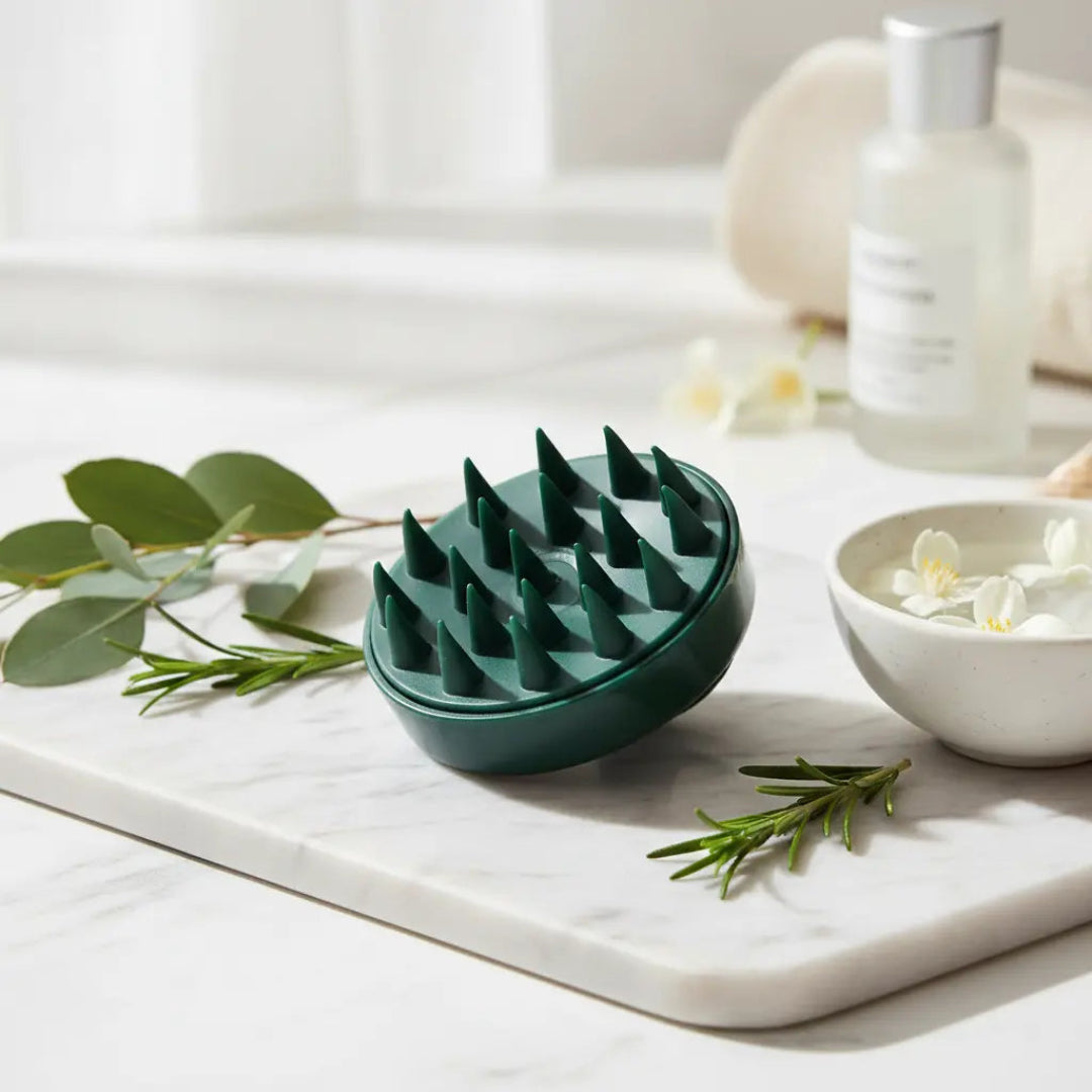 Green textured bowl on a marble surface with greenery and a bottle in the background
