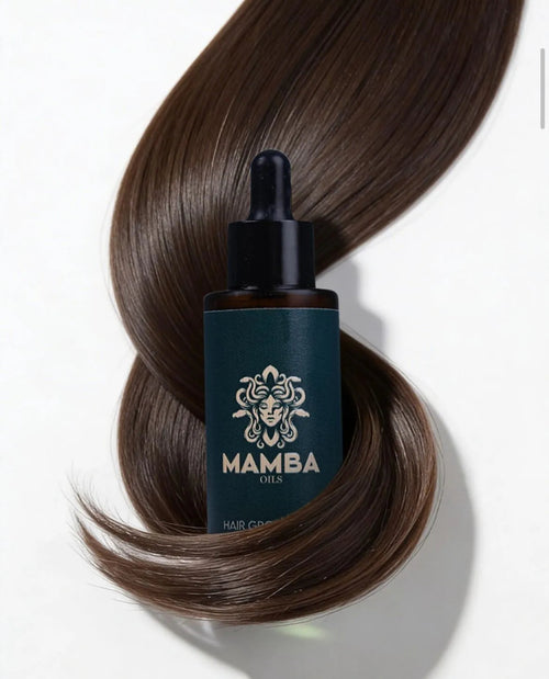 Mamba Oils hair care product with a dropper on top of wavy brown hair against a white background